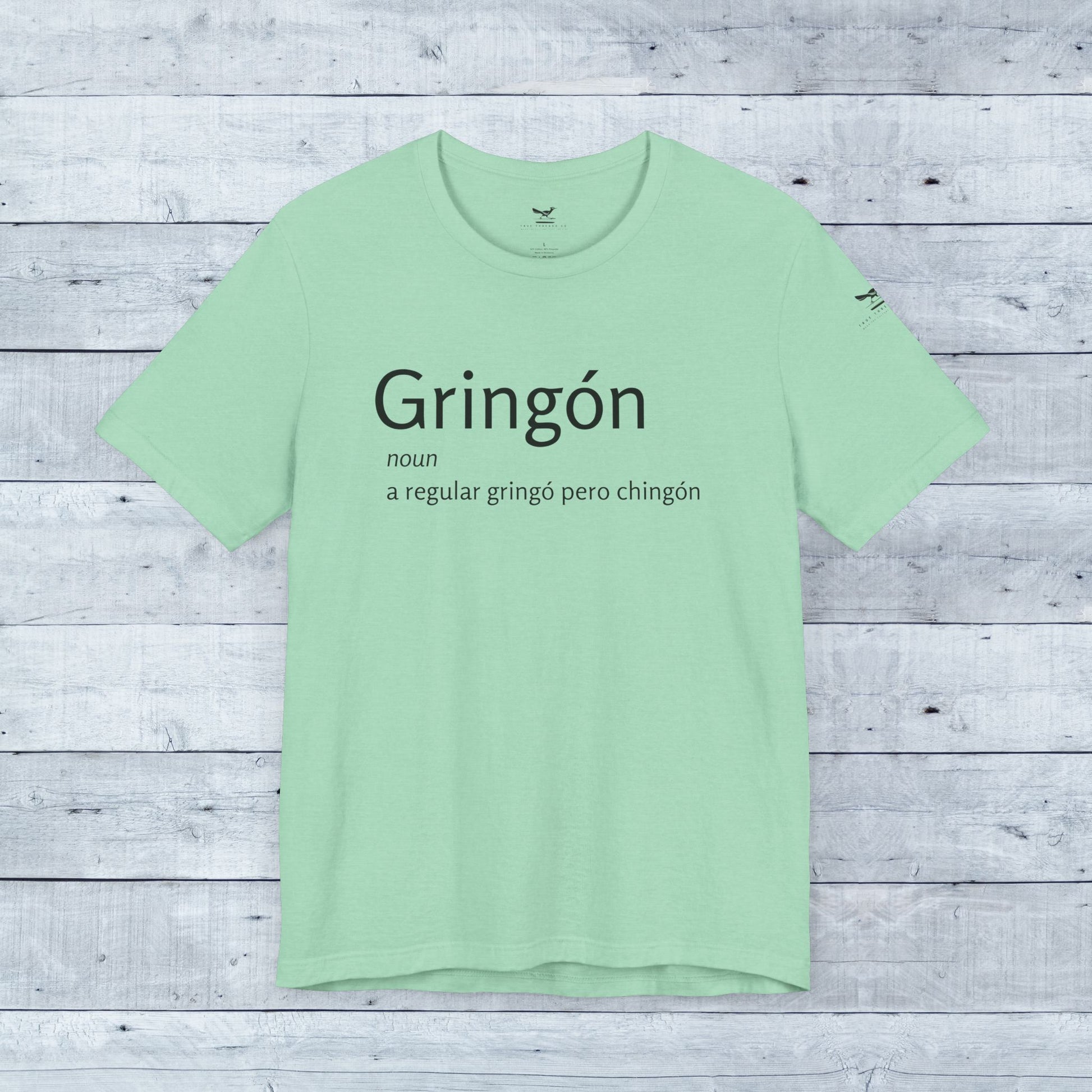 Gringón Tee close-up displays bold black text on soft green fabric, a stylish unisex crew neck for confident, cultural expression and comfort.